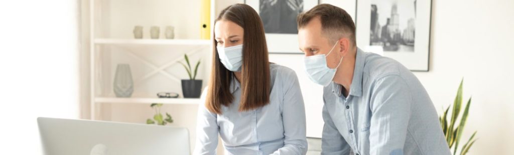 empleados con mascarilla consultando en el ordenador