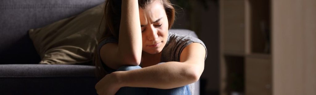 mujer preocupada sentada en un sofa