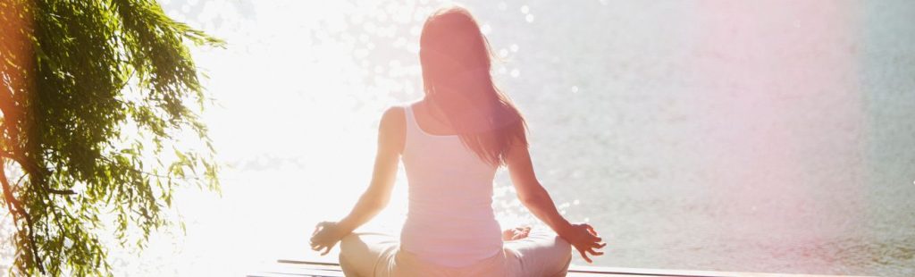 mujer meditando en la orilla de un lago