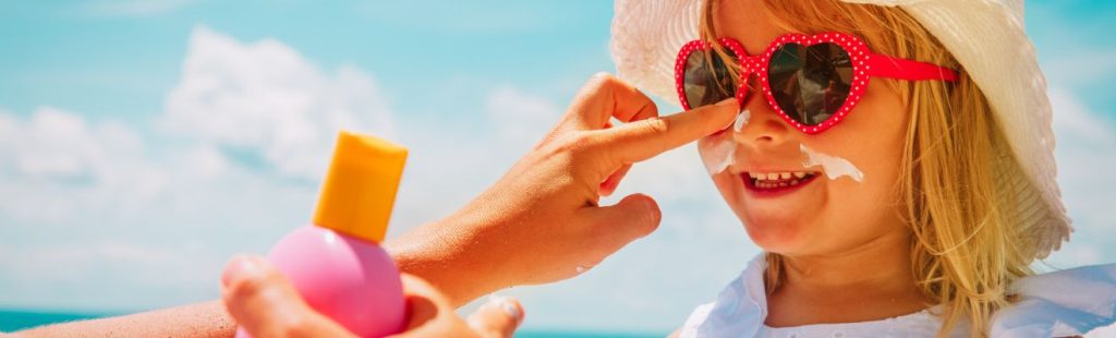 niña con crema solar en la playa