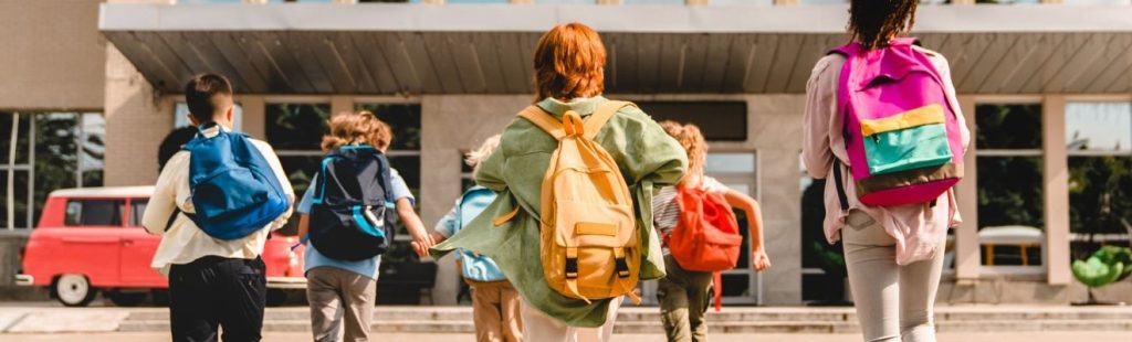 niños con mochilas entrando en colegio