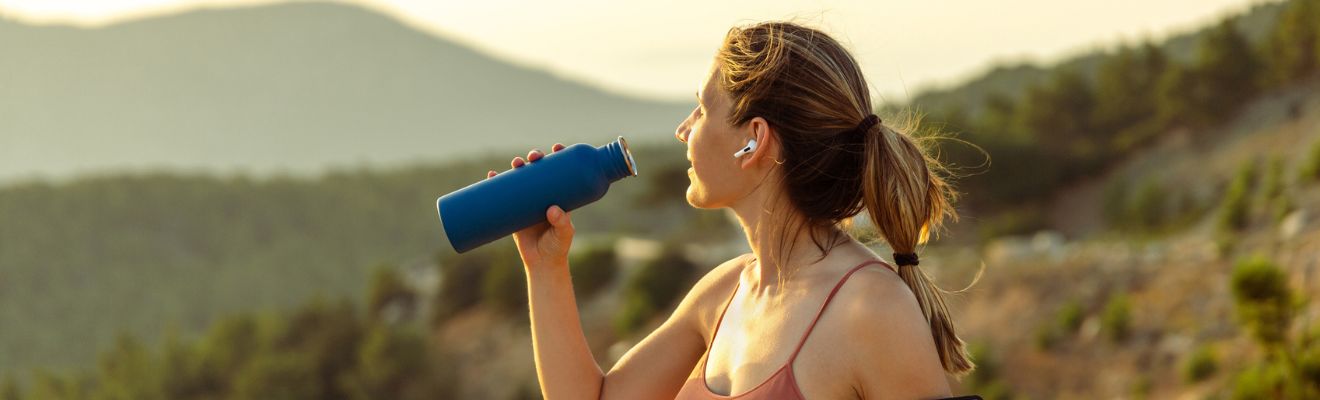 mujer hidratándose en un parque forestal